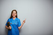© Yuriy Shevtsov - Smiling student woman doctor or nurse with medical education holding book and pointing finger. Isolated portrait of female medical worker.