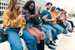 © Carlo - crowd of multiethnic young people sitting in line outdoors surfing cyberspace with cell phone