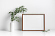 © nikavera - Blank picture frame mockup in scandinavian style over white wall with green eucalyptus in vase