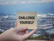 Motivational and inspirational wording. Challenge yourself written on a notepad. With blurred styled background.