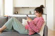 © deniskomarov - Smiling girl texting on her smartphone on social media at home on the sofa