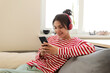 © deniskomarov - Modern  girl in wireless headphones sit relax on couch listening to music and chatting with her friends