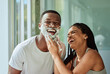 © S Fanti/peopleimages.com - Skincare wellness, happy couple in bathroom and shaving face with product for facial treatment. Laughing together in home, natural beauty and funny girlfriend helping black man with cream application