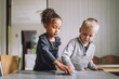 © Maskot - Multiracial male and female students cleaning dining table at kindergarten