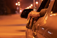 Drunk Man Driving A Car With A Bottle Of Beer At The Night. Don't Drink And Drive Concept