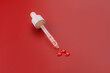 © IKvyatkovskaya - Dropper glass bottle cap mockup. Cosmetic pipette. red background. Concept of anti age and beauty cosmetics. minimalism, skin care