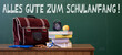 Alles Gute zum Schulanfang Hintergrund Karte mit deutschem Text - Grüne Schultafel, Schulranzen, Schulbücher und Apfel auf Lehrerpult in Klassenzimmer einer Schule