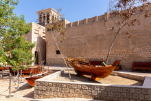 Small Traditional Wooden Rowing Boats - Abras , With Al Fahidi Old Fort Walls In The Background, Al Fahidi Historical District, Dubai, United Arab Emirates.