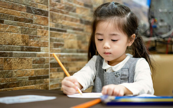 Fototapete - Back to school. Happy smiling pupil drawing at the desk. Cute little preschooler child drawing at home. Kid girl drawing with pencils
