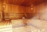 Interior of Finnish sauna, classic wooden sauna with hot steam. Russian bathroom. Relax in hot sauna with steam. Wooden interior baths, wooden benches and loungers accessories for sauna, spa complex