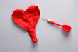 Dart and inflates red heart shaped balloon on gray background. Love concept