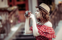 Beautiful Women In Red Polka Dot Dress And Hat With Retro Camera In The City