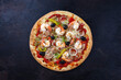 Traditionelle italienische Pizza frutti di mare Riesengarnelen, Tunfisch und Oliven serviert als Draufsicht auf einem rustikalen schwarzen Board 