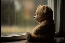  A Teddy Bear Sitting In Front Of A Window With Rain Drops On It's Glass And A Raindrops On The Window Pane Behind It, And A Blurry Background Of A Building.