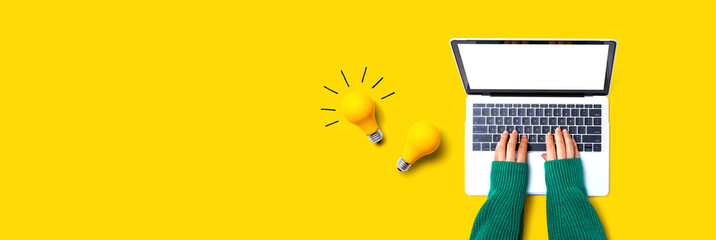 Person using a laptop computer and light bulbs - Flat lay