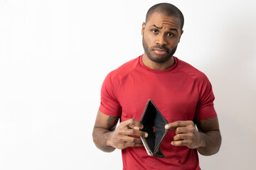 Handsome bald dark-skinned man showing an empty wallet on white background in studio with copy space.