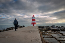 Man Walking To A Lighthouse In Portimao, Portugal.