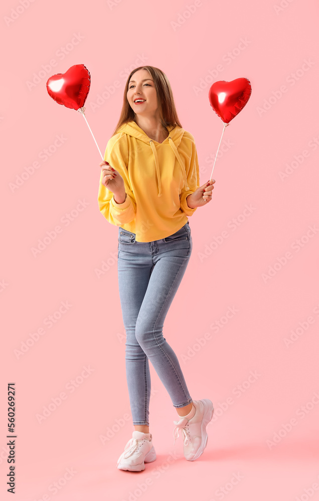 Young woman with heart-shaped balloons on pink background. Valentine's Day celebration