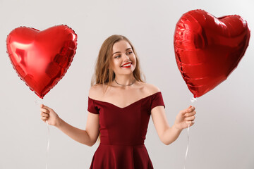 Wall Mural - Happy young woman with heart-shaped balloons on light background. Valentine's Day celebration