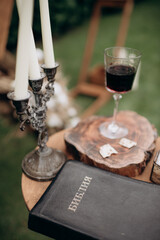 Wall Mural - wedding rings, candles, a glass of wine and a bible on the table near wedding arch