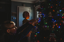 Boy And Girl Decorating Christmas Tree With Colored Lights