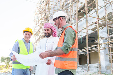 Wall Mural - Diverse team of professionals using tablet computers on construction site. Real estate construction project. with civil engineers, architects, Arabic business investors and explorer with theodolite