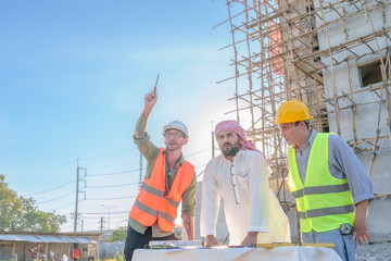 Wall Mural - Diverse team of professionals using tablet computers on construction site. Real estate construction project. with civil engineers, architects, Arabic business investors and explorer with theodolite