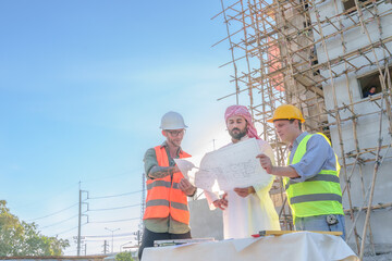 Wall Mural - Diverse team of professionals using tablet computers on construction site. Real estate construction project. with civil engineers, architects, Arabic business investors and explorer with theodolite