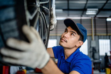 Wall Mural - Auto mechanic repairman checking tire condition and suspension in the garage changes spare parts, checks the mileage of the car, checking and maintenance service concept.