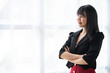 © crizzystudio - Portrait of successful confident pretty, young Asian businesswoman or freelancer standing near work desk in office, wearing formal stylish clothes, arms crossed, looking at camera, smiling friendly