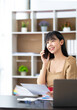 © crizzystudio - Happy young asian woman talking on the mobile phone and smiling while sitting at her working place in office.