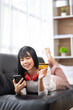 © crizzystudio - Asian woman using credit card and mobile phone for online shopping At home while lying on the phone for online shopping and online payment concept with credit card