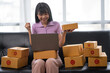 © crizzystudio - Asian women working SME business at the workplace at home. use laptop to check customer orders online shipping boxes, freelance SME entrepreneur online business idea.