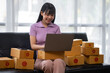 © crizzystudio - Asian women working SME business at the workplace at home. use laptop to check customer orders online shipping boxes, freelance SME entrepreneur online business idea.