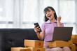 © crizzystudio - Asian women working SME business at the workplace at home. use laptop to check customer orders online shipping boxes, freelance SME entrepreneur online business idea.