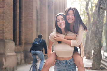 Wall Mural - young women in love smiling happy piggyback with her girlfriend during their date, concept of friendship and love between people of the same sex