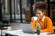 Leinwandbild Motiv Attractive african young confident woman holding coffee cup and using laptop computer, sitting at open co-workspace.