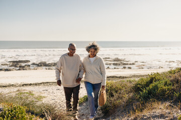 Wall Mural - Cheerful elderly couple leaving the beach after a picnic