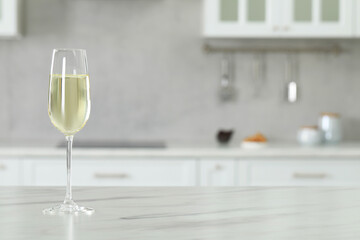 Glass of wine on white marble table in kitchen. Space for text