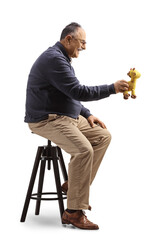 Poster - Profile shot of a mature man sitting on a chair and holding a giraffe toy