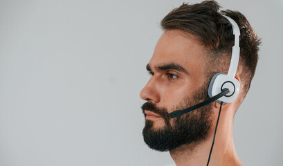 Wall Mural - Side view. In headset. Handsome man is in the studio against white background