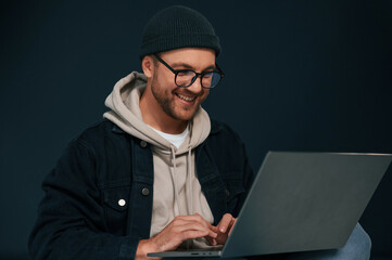 Wall Mural - Using laptop and smiling. Handsome man is in the studio against background