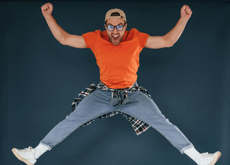 Wall Mural - Jumping, feeling good, excited. Handsome man is in the studio against blue background