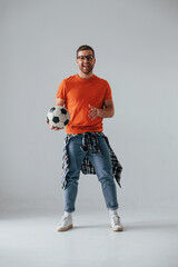 Wall Mural - Standing and holding soccer ball. Handsome man is in the studio against white background