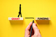 Grant funding symbol. Concept words Grant funding on wooden blocks. Beautiful yellow table yellow background. Businessman hand. Businesswoman icon. Business and grant funding concept. Copy space.