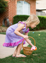 Side View Of Girl Collecting Easter Egg In Basket At Backyard