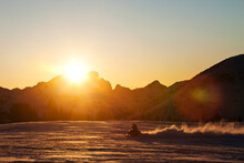 A Athletic Young Man Snowmobiling At Sunset In Montana.