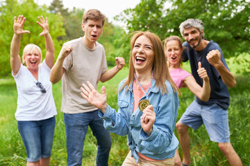 Cheering team and young woman with winner medal