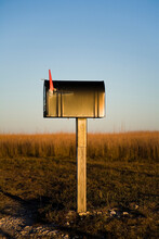 A Mailbox Stands Alone In A Kansas Corn Field As The Sun Sets Beyond The Horizon.