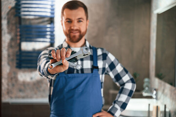 Wall Mural - Bunch of wrenches in hand. Plumber in blue uniform is at work in the bathroom